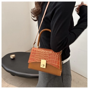 Détail du sac à main en cuir gaufré crocodile avec fermoir doré et poignée cylindrique