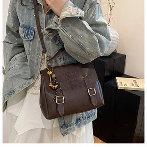 Detail of vintage dark brown faux leather bag with metal buckles and decorative charm set