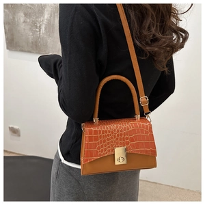 Détail du sac à main marron avec texture crocodile, fermoir en métal et bandoulière réglable