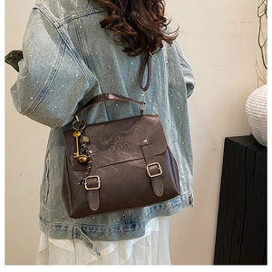 Detail view of deep brown vintage PU leather backpack with embossed letters and gold buckle