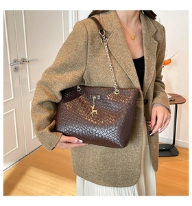 Detailed view of dark brown woven tote bag featuring a gold deer pendant on a model