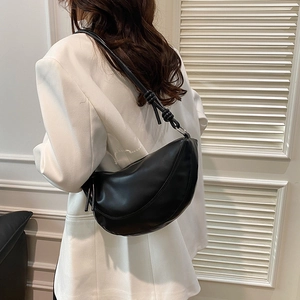 Fashionable black half-moon shoulder bag with unique knot detail for women on model