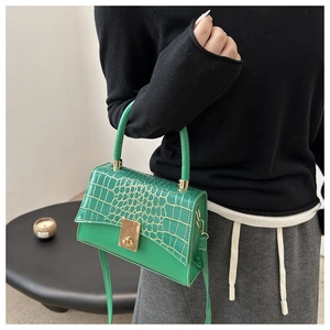 Détail du sac bandoulière vert avec rabat motif crocodile et fermoir doré rotatif