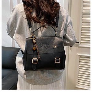 Detail shot of the black PU leather backpack with COIN embossing and gold bell charm