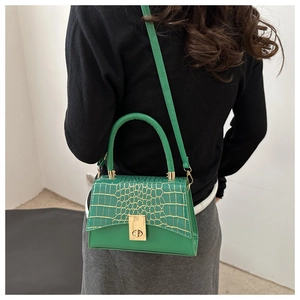 Détail du sac à main vert motif croco avec fermoir doré porté en sac à bandoulière