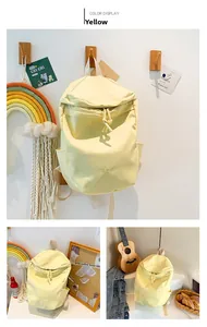 Detail of yellow nylon backpack featuring embroidered Bag lettering and side pockets