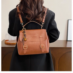Detail of a brown leather backpack with 'COIN' embossed texture and metallic buckle