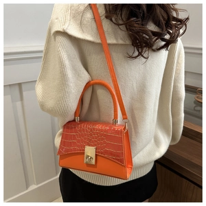 Vue détaillée du sac à bandoulière orange avec texture crocodile et fermoir rotatif doré