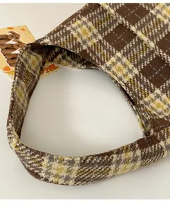 Close-up of wide handles and thick plaid fabric texture on a brown tote bag