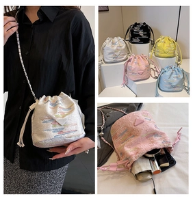 Detail view of colorful embroidered bucket bag with drawstring and metal chain strap