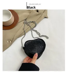 Detail of heart-shaped black glitter mini chain bag with silver strap for party wear