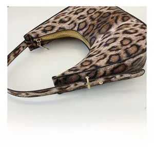 Detailed view of leopard print crescent bag showing adjustable strap and gold metal buckle