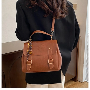 Detail view of vintage brown leather backpack worn as a crossbody bag with buckle straps