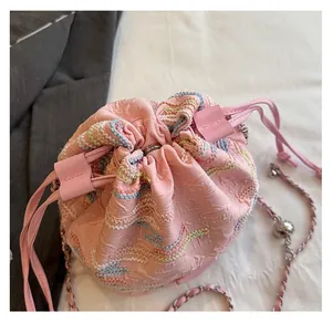Detail of pink drawstring bucket bag showing colorful wave embroidery and chain strap