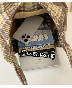 Detail view of the spacious plaid tote bag interior holding an iPad and notebook