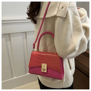 Détail d'un sac à main rose à texture crocodile avec fermoir tournant en métal doré