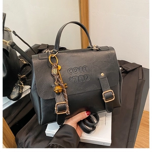 Detail of a vintage black leather backpack featuring COIN 7ND embossing and metal charms