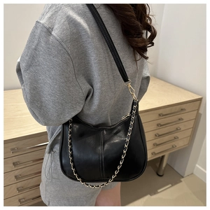 Détail du sac hobo en similicuir noir avec chaîne dorée et large bandoulière épaule