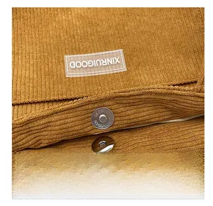 Close-up of brown corduroy tote bag showing the magnetic buckle and brand logo patch