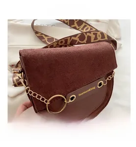 Détail de la besace marron mate avec chaîne dorée et bandoulière à motif géométrique