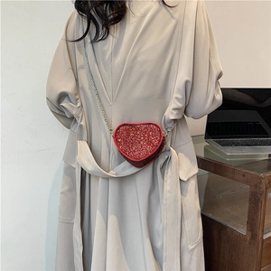 Mini heart-shaped red rhinestone crossbody bag with silver chain strap on model