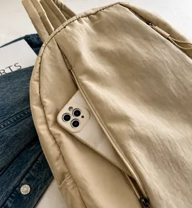 Detail view of the beige nylon backpack side pocket with a smartphone inside