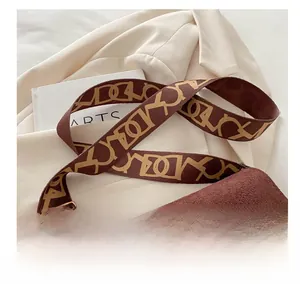 Détail de la large bandoulière jacquard sur une sacoche en cuir mat marron