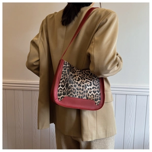 Detailed back view of a vintage leopard print shoulder bag with red leather trim on a model