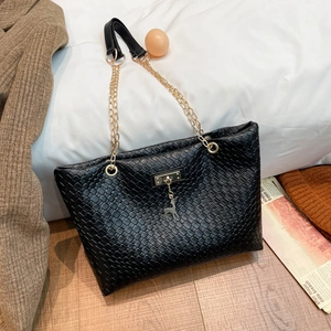 Elegant black woven tote bag with gold deer pendant and chain strap in a lifestyle setting