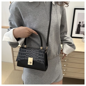 Détail du rabat à motif crocodile noir et du fermoir rotatif doré sur le sac à main