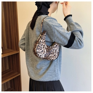 Detailed close-up of a leopard print crescent handbag styled with a cozy gray sweater