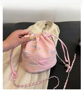 Detailed view of pink drawstring bucket bag with colorful wavy embroidery and metal logo