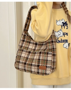 Detail of the brown plaid hobo bag with a leather brand label and wide shoulder strap