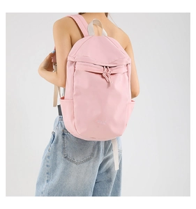 Detail view of light pink nylon backpack featuring a drawstring pocket and side water bottle slot