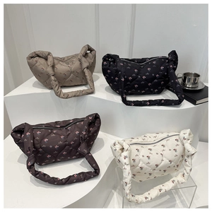 Bolsos acolchados con flores en beige negro marrón y blanco en un soporte de exhibición