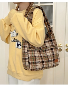 Detail of vintage plaid tote bag showing textured tweed fabric and side leather label
