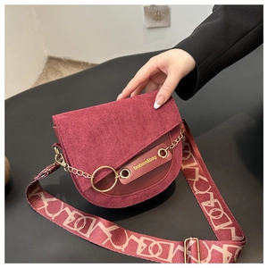 Détail du sac selle bordeaux avec rabat en daim et large bandoulière décorée
