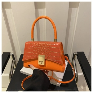 Détail du sac orange avec texture crocodile et fermoir rotatif en métal doré élégant