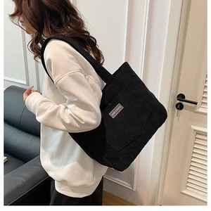 Detailed texture of black corduroy tote bag featuring XINRUIGOOD brand label and wide strap