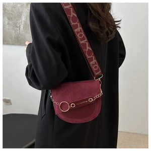 Détail de sac besace bordeaux avec chaîne dorée et large bandoulière à motifs
