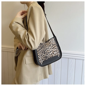 Side view of leopard print underarm bag paired with a beige blazer for a retro style look