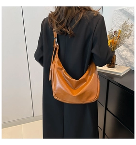 Borsa a mezzaluna marrone in similpelle con tracolla regolabile indossata da una modella