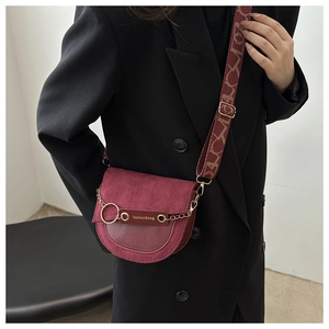 Détails du sac selle bordeaux montrant la large bandoulière et l'anneau doré