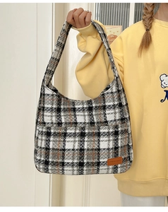 Close-up of large plaid tote bag with brown leather label and thick tweed texture detail