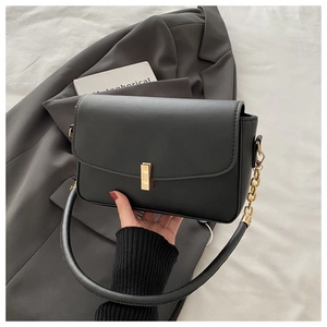Detailansicht der schwarzen Ledertasche mit goldener Metallschnalle und eleganter Kette