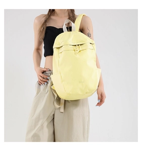 Detail of light yellow nylon backpack with dual zippers, side pocket, and BAG logo