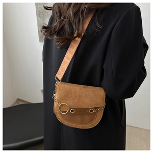 Détail du sac selle marron rétro avec chaîne dorée et large bandoulière tissée