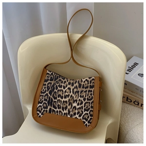 Detail view of leopard print texture and brown leather strap on vintage shoulder bag