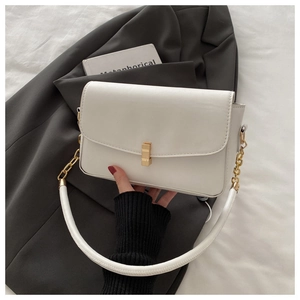 Detailansicht der cremefarbenen Tasche mit goldenem Metallverschluss und Kettenriemen