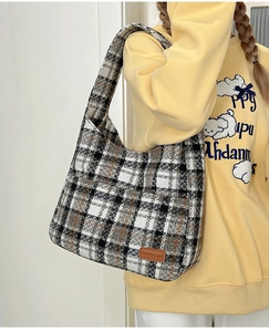 Detail of tweed checkered shoulder bag with premium leather logo patch and texture